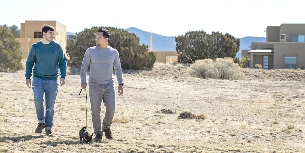 Walking a dog in the HomeWise neighborhood surrounded by the natural Santa Fe landscape