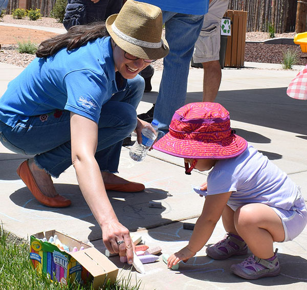 Woman and child drawing with chalk on sidewalk